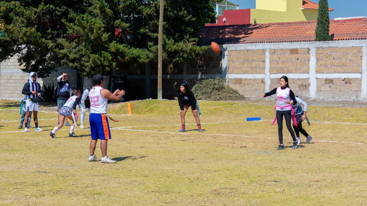 Energetic youth flag football match on a sunny day in Toluca de Lerdo, Mexico, with players in action.